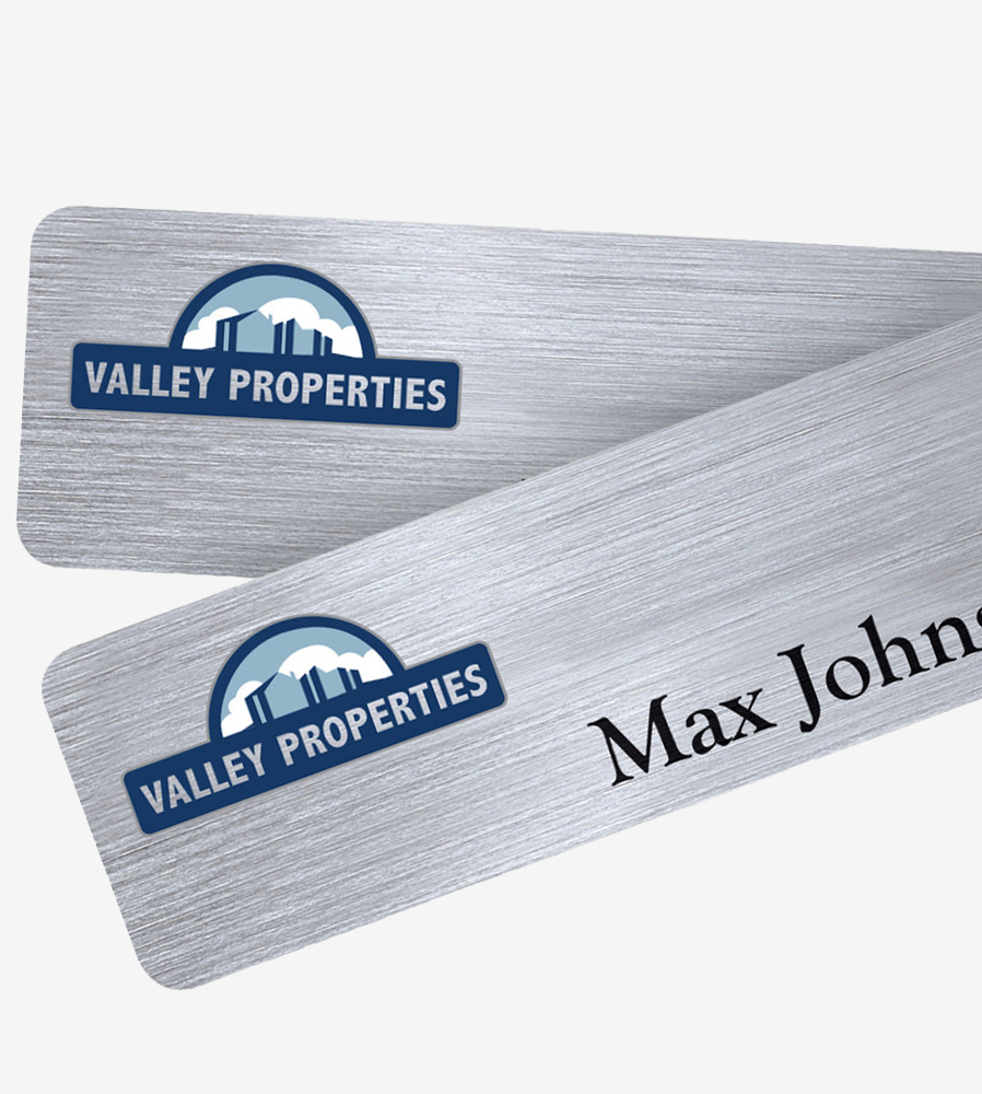 silver colored metal name badge with company logo and a person's name
